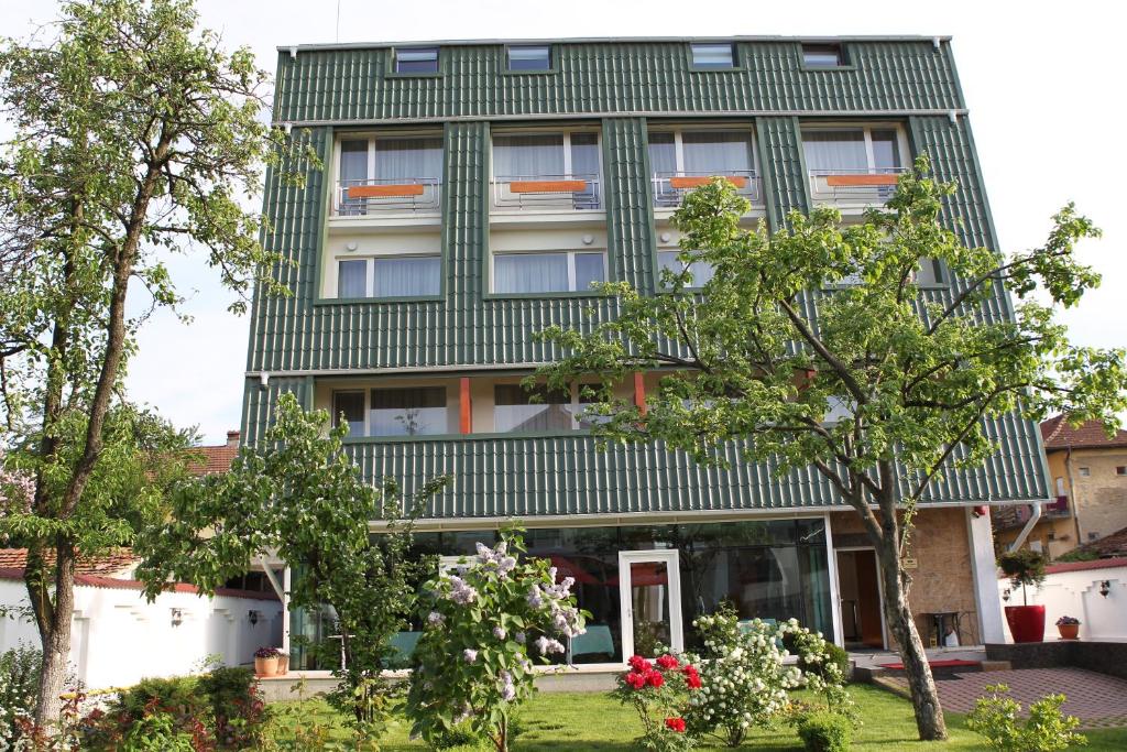 un bâtiment vert avec des arbres devant lui dans l'établissement Hotel Jasmine, à Braşov