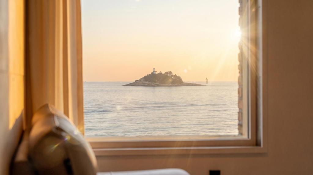 a window view of the ocean with a island in the distance at Sokcho Moreve Pension in Sokcho