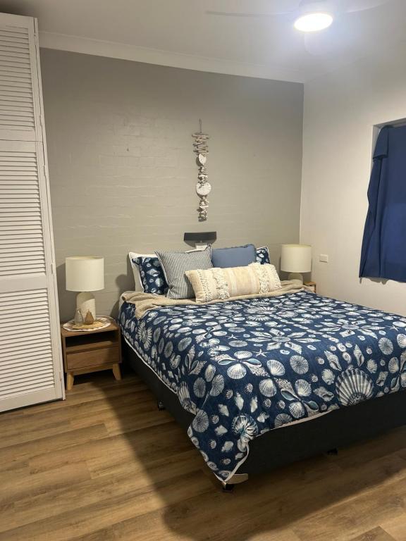 a bedroom with a bed with a blue comforter and two lamps at Coasters 27 in Sawtell