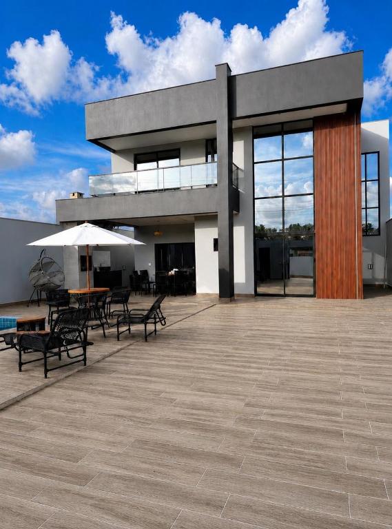 a building with a patio with tables and chairs at Casa Aconchegante em Japaratinga in Japaratinga