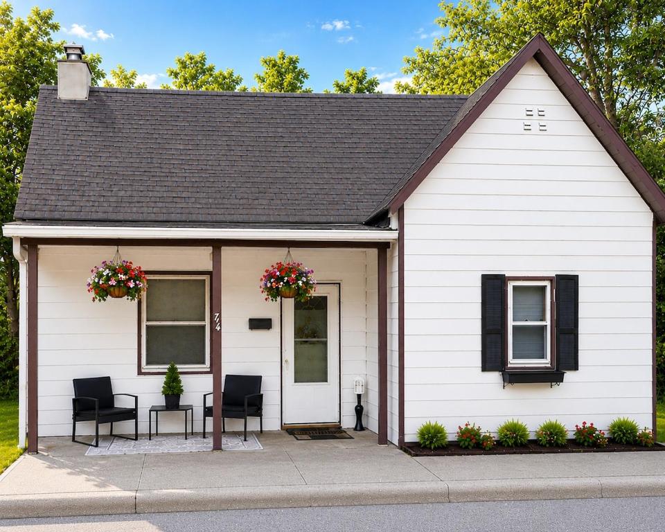 a white house with two chairs and two windows at Downtown 2 BR Cottage Close to IU in Bloomington