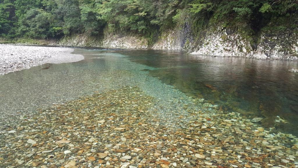 a body of water with rocks and a rocky shore at Aoi-Yane Traditional Japanese House in Kumano Kodo Nakahechi in Tanabe