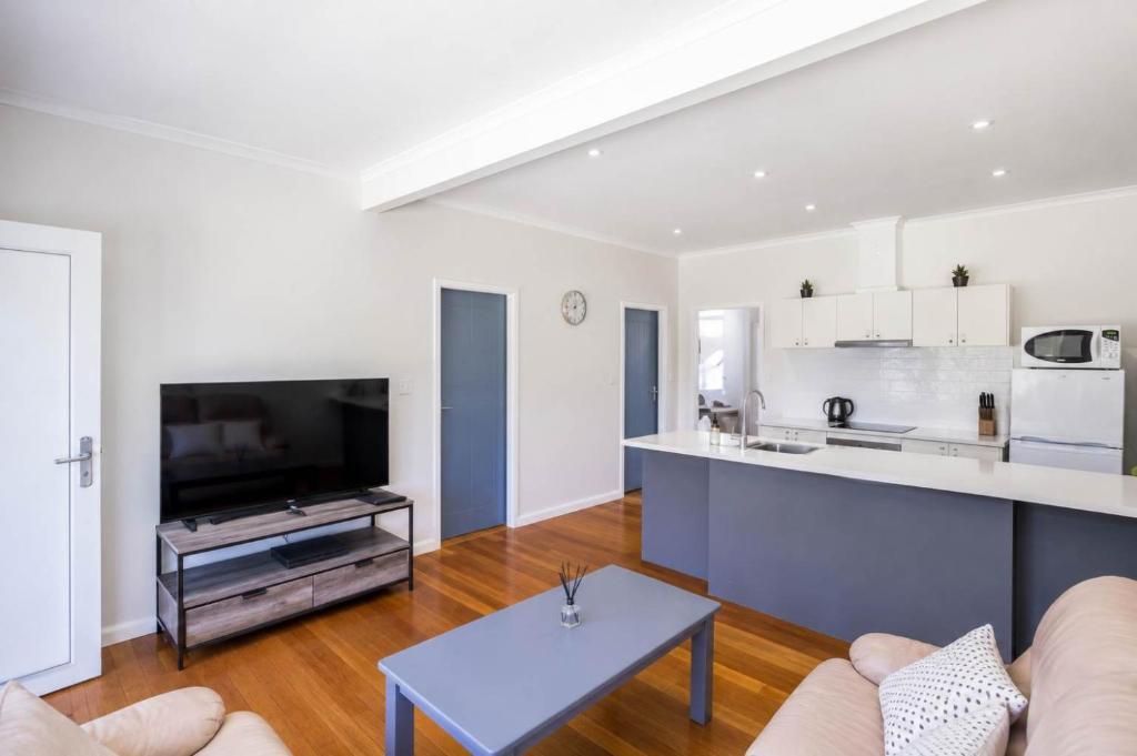 a living room with a couch and a kitchen at Harbour Breeze - apartment in Ulladulla in Ulladulla
