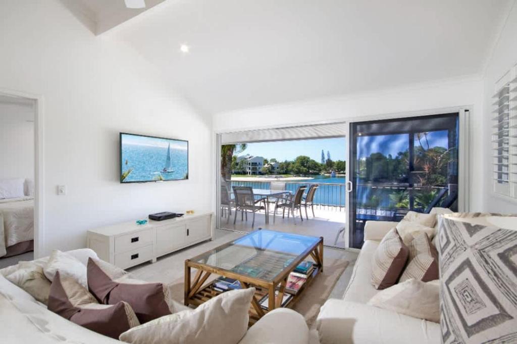 a living room with white furniture and a view of the ocean at Noosa Haven Apt 12 Riverfront Elegance in Noosaville