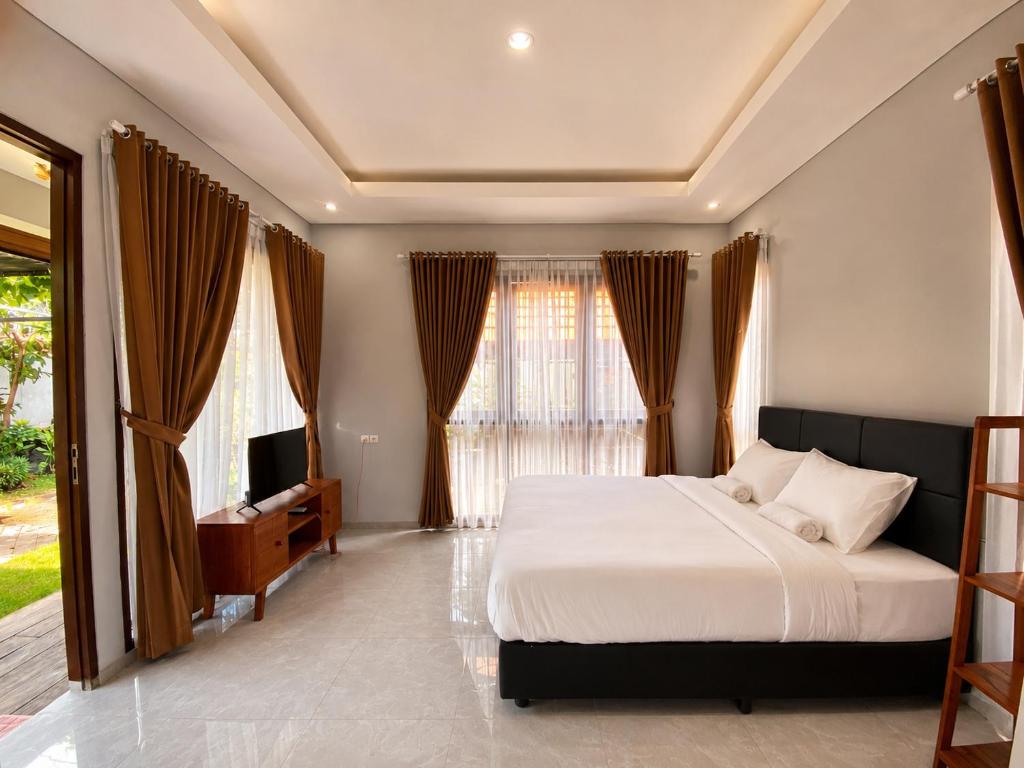 a bedroom with a bed and a tv and windows at Pondok DlodPoh in Karangasem