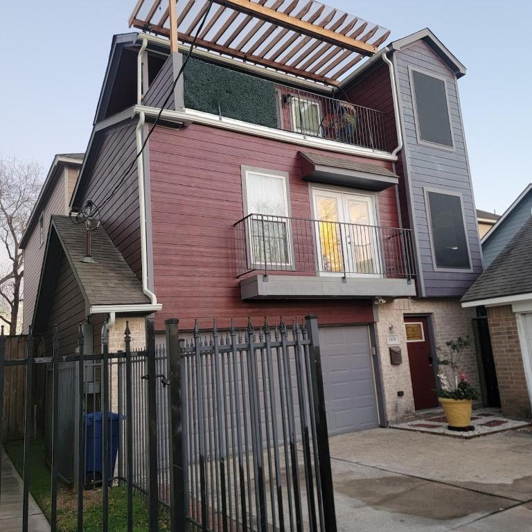 a red house with a fence in front of it at Houston Sweet Spot Townhouse in Houston