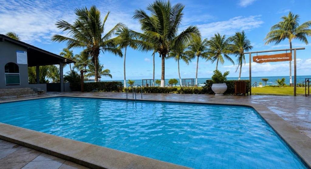 a large swimming pool with palm trees in the background at Flat Carneiros - Hotel Marinas in Tamandaré