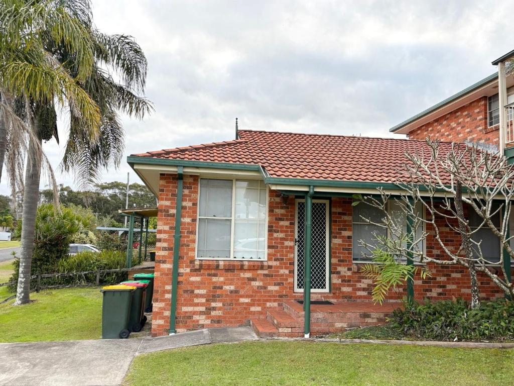 a brick house with a palm tree in front of it at Chalkers Unit - Bring your own linen in South West Rocks