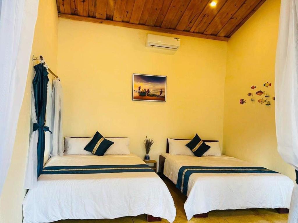 two beds in a room with yellow walls at Twin Double Room in Phú Ngọc (1)