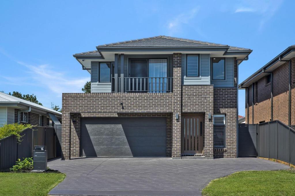 a brick house with a garage and a fence at Serenity Place in Mannering Park