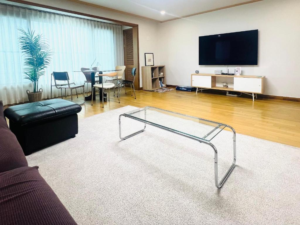 a living room with a glass coffee table and a flat screen tv at Pinkliey House in Ilsan-yŏk