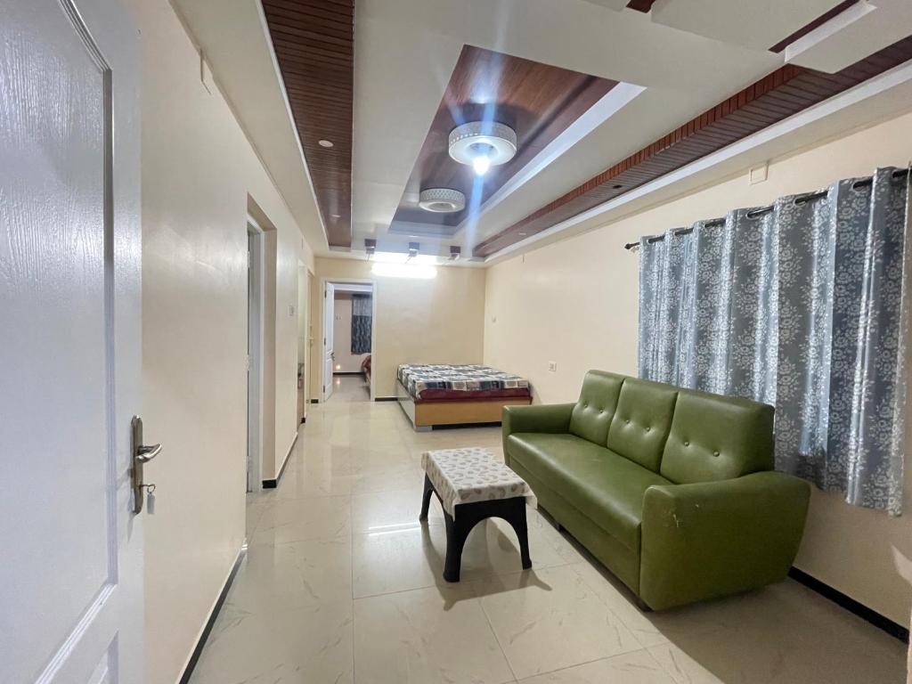 a waiting room with a green couch and a bed at Nilgiris Stayz - Home Stay at Ooty in Ooty