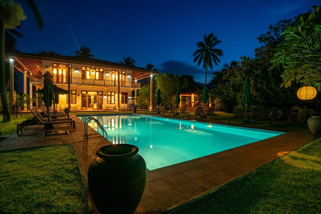 a swimming pool in front of a building at night at Jim's Farm Villas in Madawala