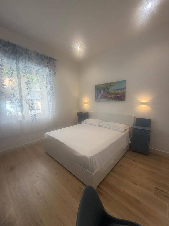 a bedroom with a white bed and a chair at Lulù Marin Rooms in Scalea