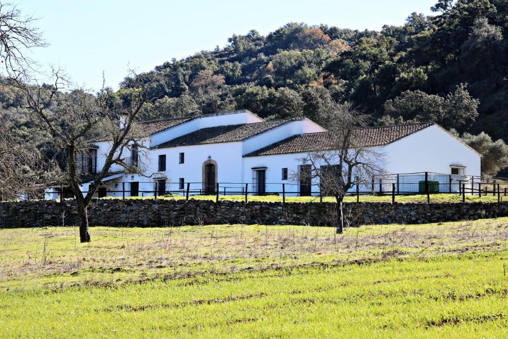 una casa blanca con una valla en un campo en Villa Escutia, en Cazalla de la Sierra