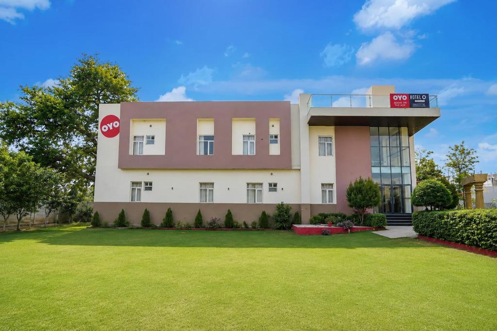 a building with a lawn in front of it at Super Hotel O Gomti Nagar Vigyan khand in Lucknow