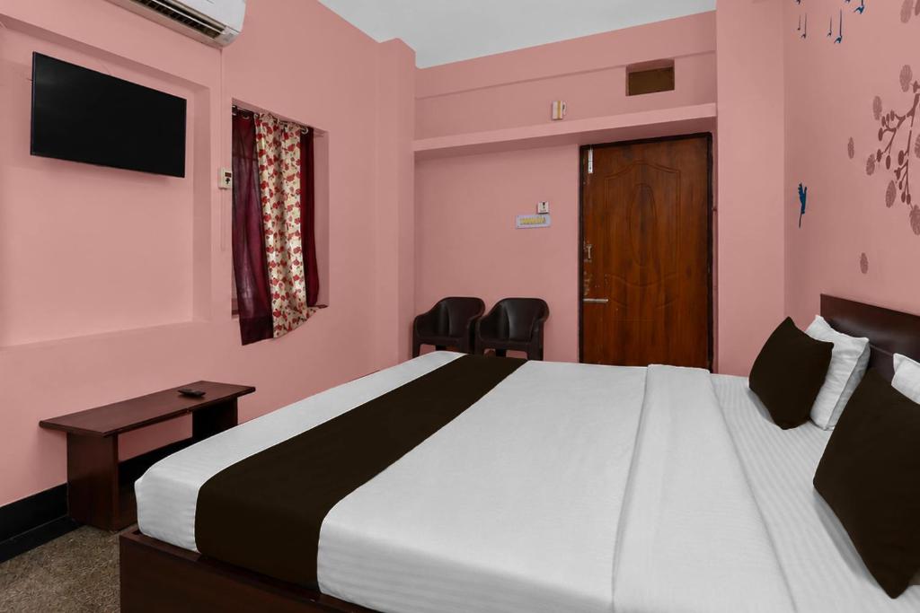 a bedroom with a large bed with pink walls at Hotel O Aarshi Palace in Cuttack