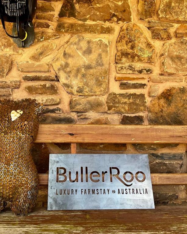 a sign in front of a stone wall at BullerRoo Luxury Chalet & Cottage Farmstay in Barwite