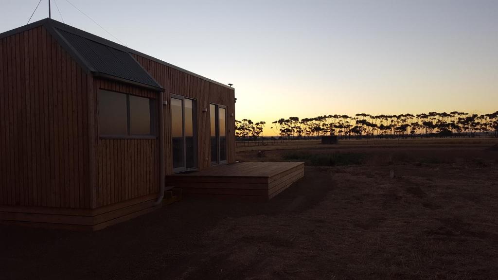 un petit bâtiment avec une terrasse couverte offrant une vue sur le coucher de soleil en arrière-plan. dans l'établissement Lara Lodge, à Lara