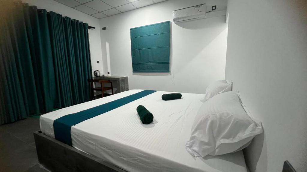 a bedroom with a large white bed with green accents at Elevara Eco Resort - Wasgamuwa in Kathurupitiya