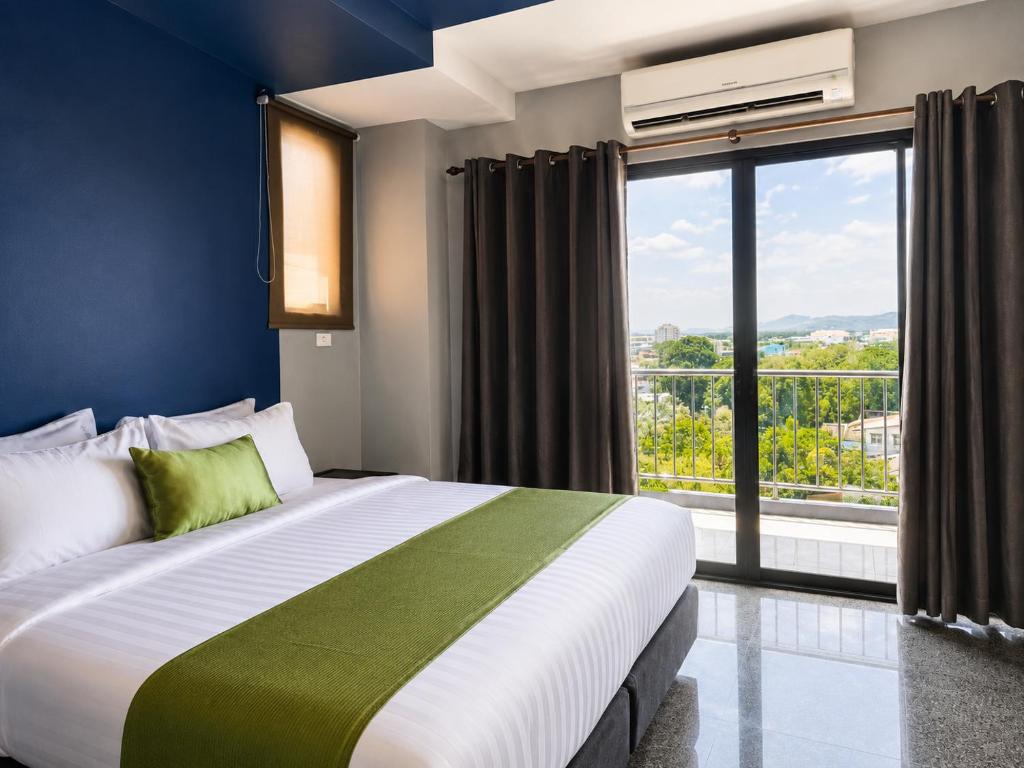 a bedroom with a large bed and a large window at iCheck inn Phuket Town in Phuket