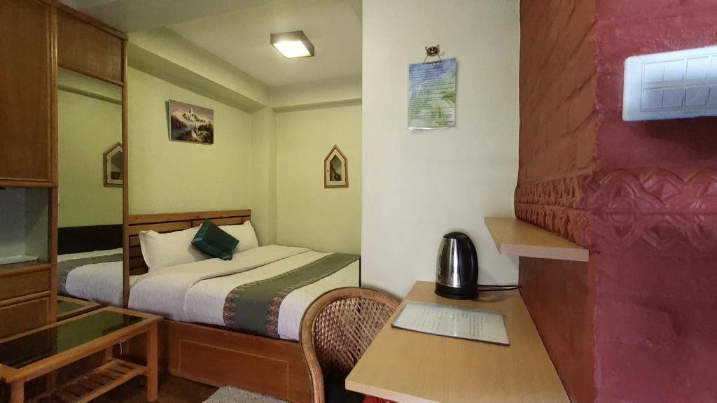 a small room with a bed and a desk with a telephone at Tranquil Haven with shared kitchen access at greentara heritage home in Pātan