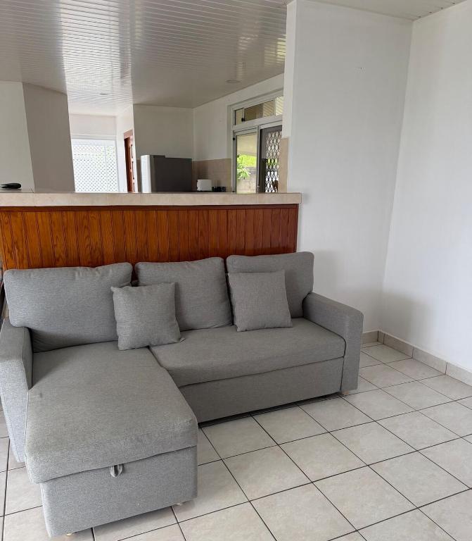 a living room with a couch and a counter at Fare Havai - Raiatea in Taputapuapea
