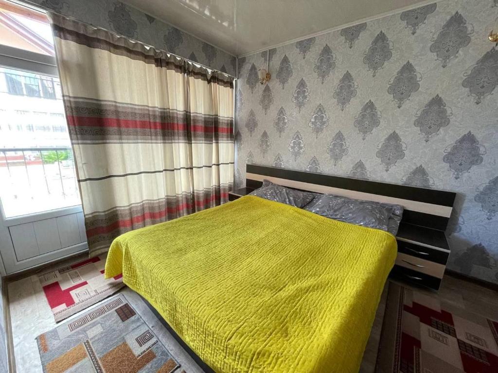 ein Schlafzimmer mit einem Bett, auf dem eine gelbe Decke liegt in der Unterkunft Baisuu in Bosteri