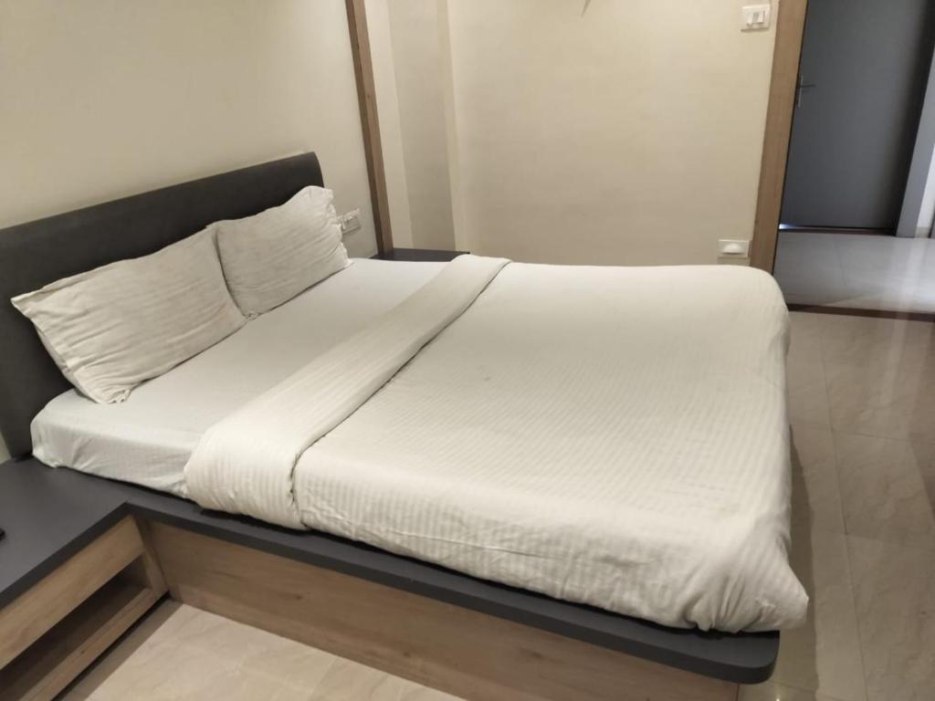 a bed with white sheets and pillows on it at Hotel Radhika in Lātūr