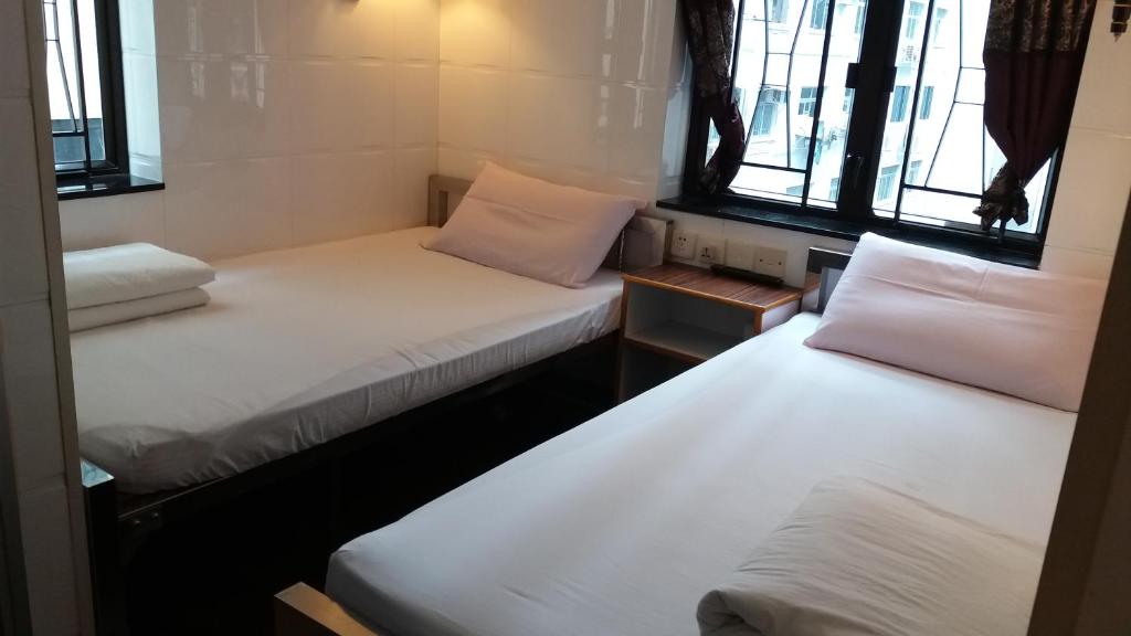 two beds in a small room with windows at Sun Shine Guest House in Hong Kong