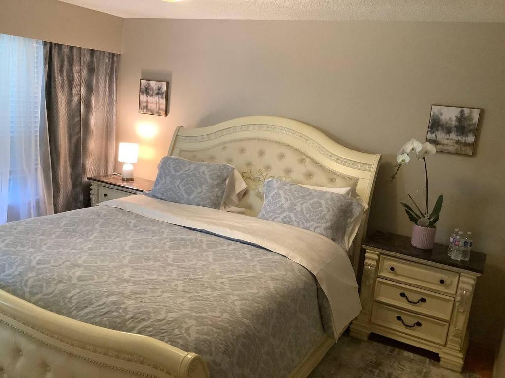 a bedroom with a bed with blue pillows and two night stands at Cozy nest in Coquitlam