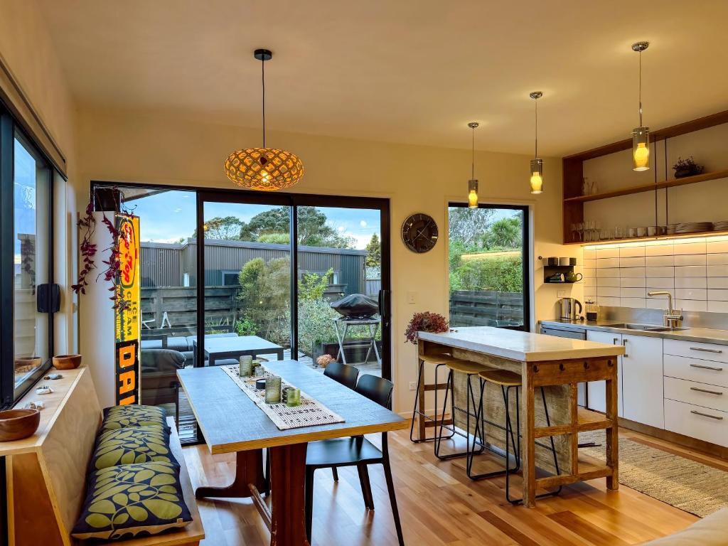 a kitchen and living room with a table and chairs at Kowhai Cabin - Serene Scandi Escape in Hokitika in Hokitika