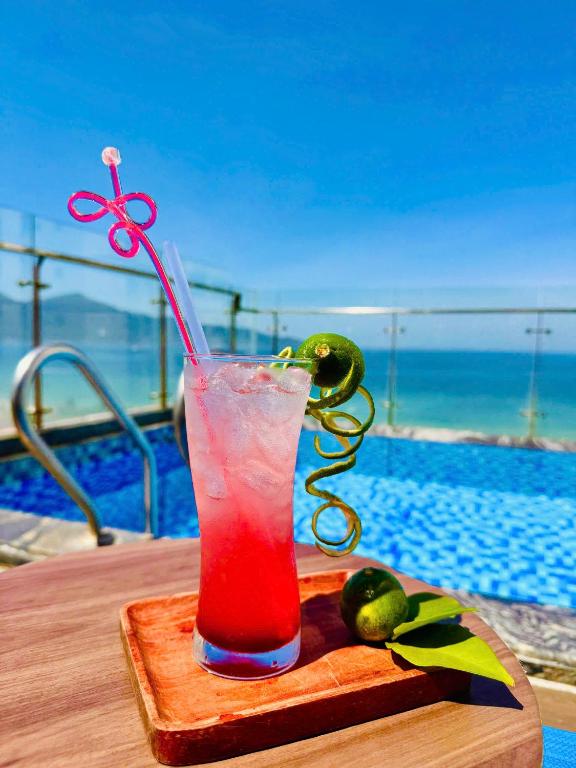 A bright red drink served beside a rooftop-looking pool with a sea view.
