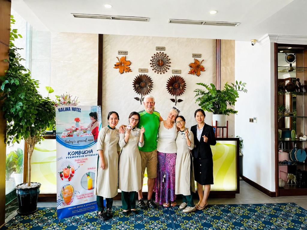 A hotel reception area photographed with staff and guests posing beside a promotional display.