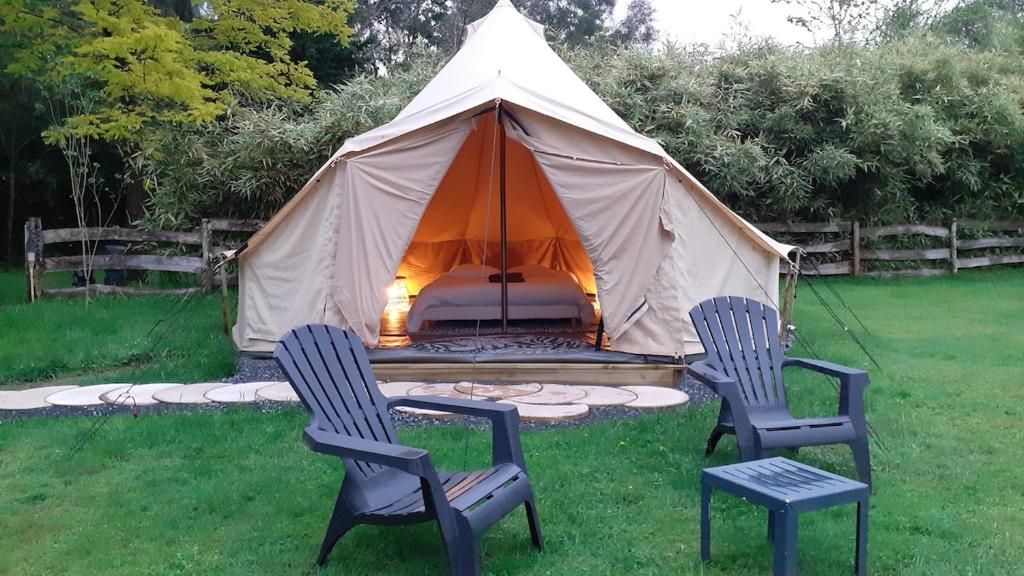two chairs and a tent in a yard at Logement insolite tente glamping in Parigné-lʼÉvêque