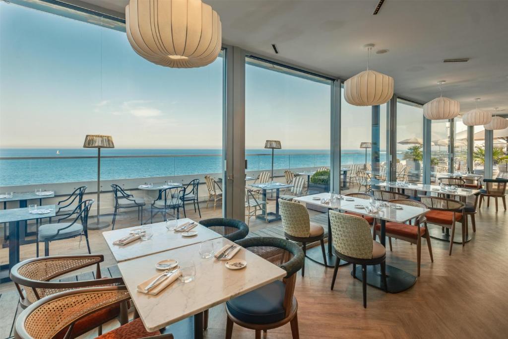 ein Restaurant mit Tischen und Stühlen und Meerblick in der Unterkunft Radisson Blu Hotel Nice in Nizza