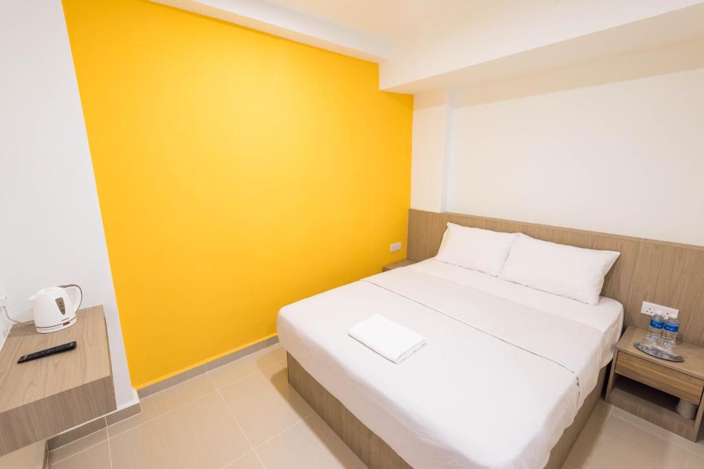 a bedroom with a white bed and a yellow wall at HomeStay 21 Hotel in Johor Bahru