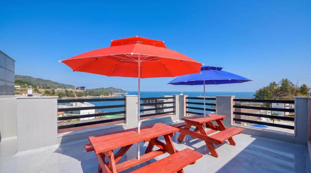 two picnic tables with umbrellas on a deck at Samcheok Jisu Pension in Samcheok
