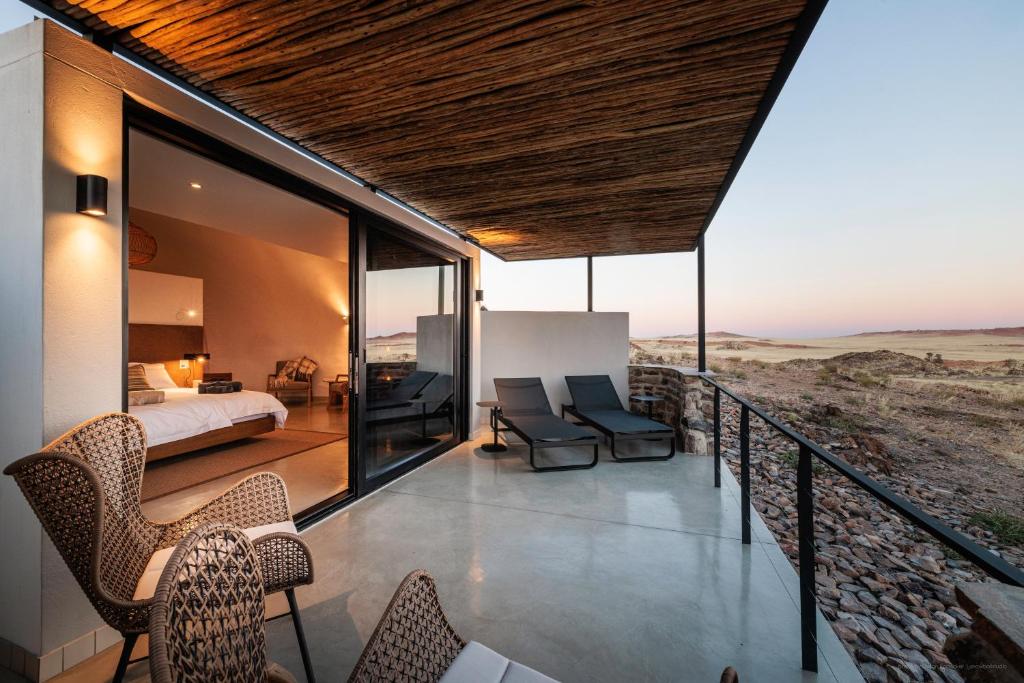 a room with a bed and chairs on a balcony at Rostock Ritz Desert Lodge in Cha-re