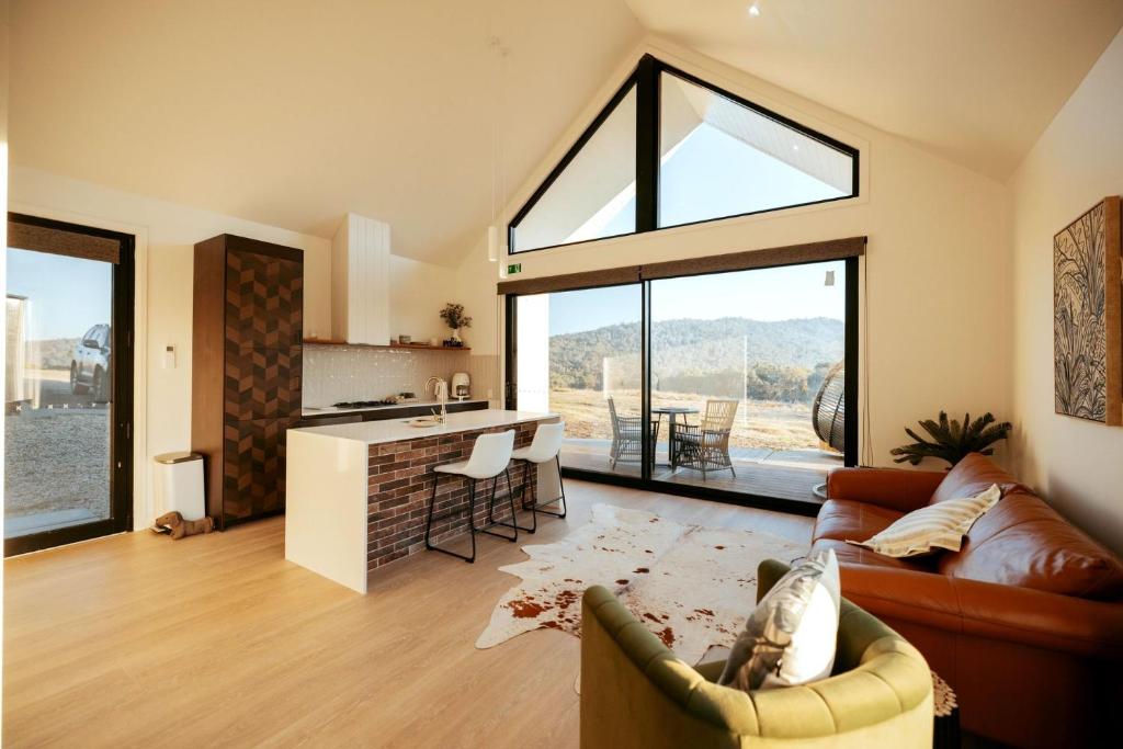 a living room with a couch and a kitchen with windows at Glenbosch - Cottage One in Beechworth