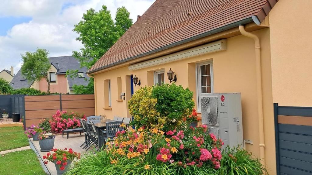 a house with a table and chairs and flowers at Gîte du Pont d 'Amourette in Mayenne
