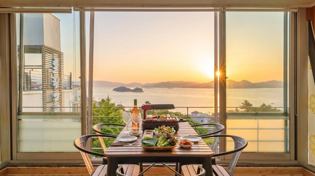 a table with a plate of food on it with a view of the ocean at Yeosu falling in blue ocean view pension in Yeosu