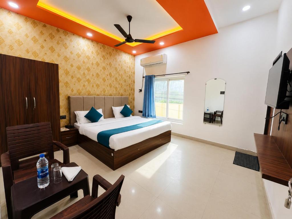 a bedroom with a bed and a table and a television at Hotel RL Ramayansh - 300 mtr From Ram Mandir Ayodhya in Ayodhya