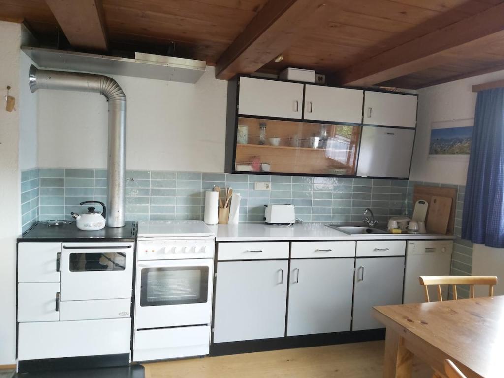 a kitchen with white appliances and a wooden table at Zimmerhäusl in Schlitters