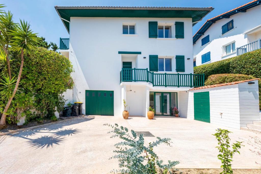 a house with white walls and green doors at Maison basque familiale Eguski Alde in Saint-Jean-de-Luz