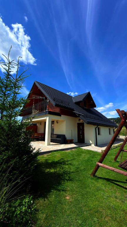 a house with a black roof and a grass yard at Domek na Hubce 2 Blisko jeziora Velo Czorsztyn in Maniowy