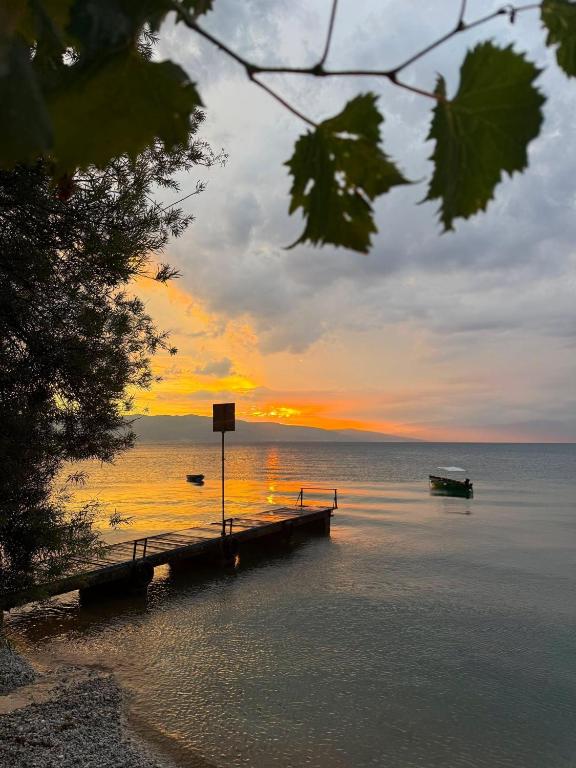 a dock with a boat on the water at sunset at Apartmani Ribar in Ohrid
