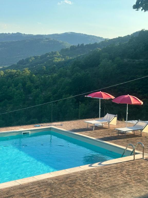 a swimming pool with two umbrellas and two chairs at Villa Sant' Andrea in Gubbio