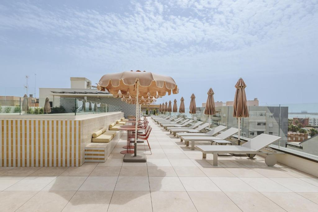 a row of chairs and an umbrella on a roof at Intelier Malvarrosa Plaza in Valencia