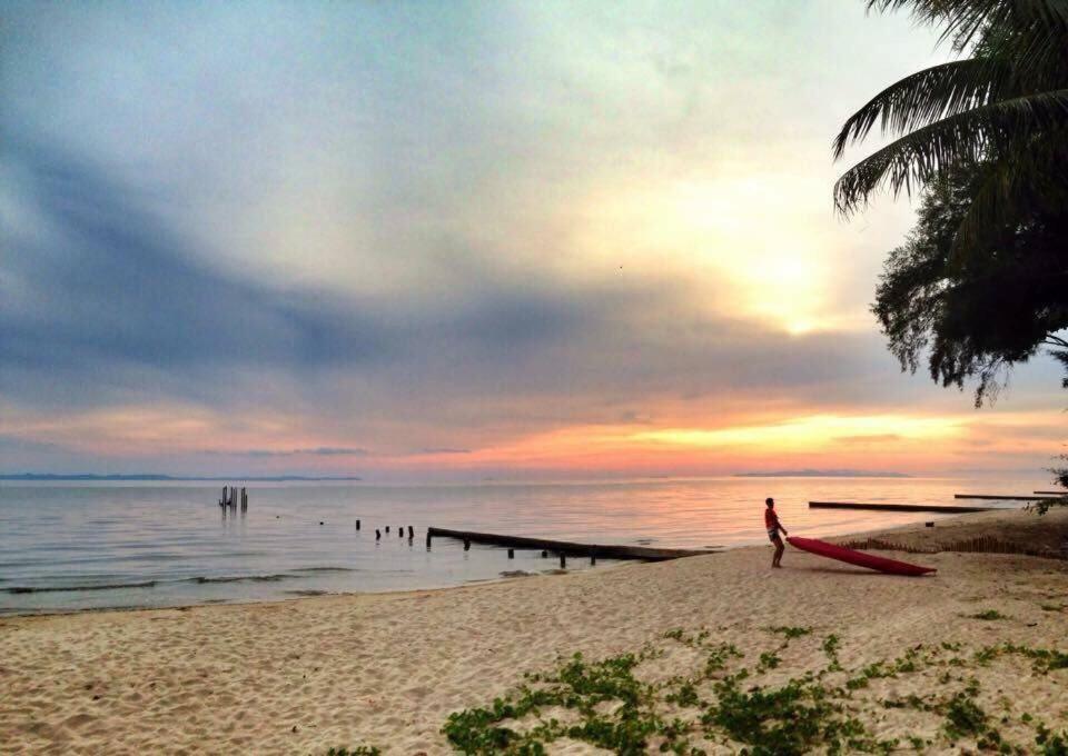 a person standing on a beach with a surfboard at Meet The Sea in Khlong Yai